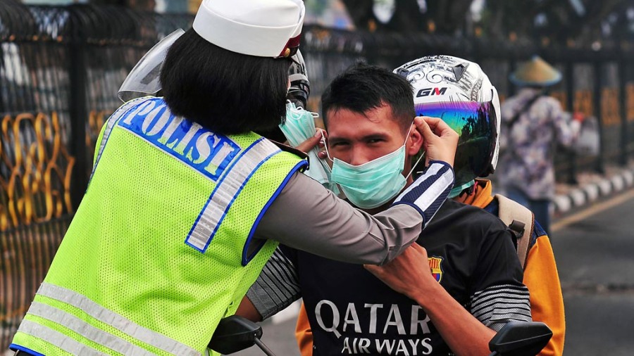 Sejumlah Polwan membagikan masker kepada warga pengguna jalan ketika kabut asap menyelimuti Kota Pekanbaru, Riau, Sabtu (5/9). Polresta Pekanbaru menurunkan puluhan Polwan untuk membagikan masker dan mengingatkan semua pengguna jalan untuk menyalakan lamp